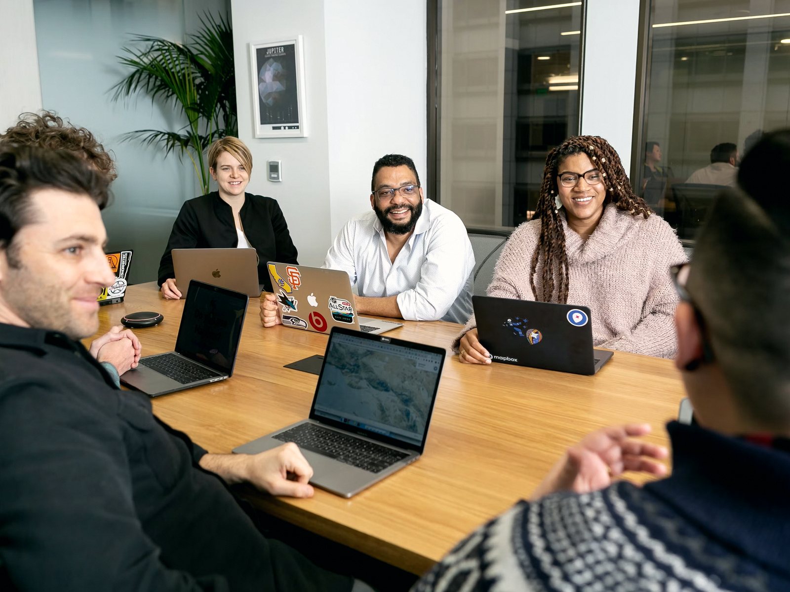 Pessoas em reunião de trabalho com notebooks em mesa de madeira